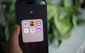 Mão segurando um smartphone com aplicativos de inteligência artificial exibidos na tela.