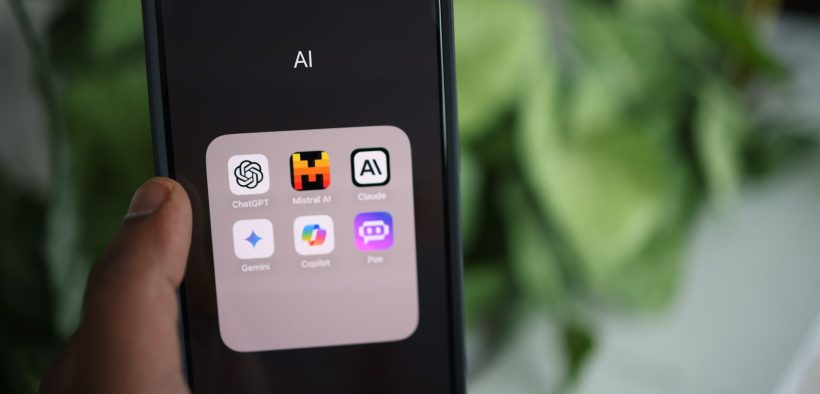 Mão segurando um smartphone com aplicativos de inteligência artificial exibidos na tela.