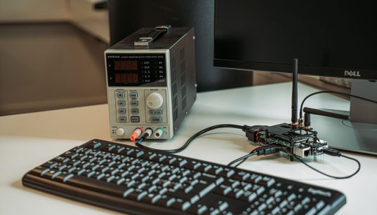 Estação de trabalho com teclado, monitor e equipamentos usados para programação e desenvolvimento de aplicações.