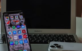 Notebook aberto ao lado de um smartphone sobre uma mesa, representando produtividade e conectividade entre dispositivos.