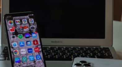 Notebook aberto ao lado de um smartphone sobre uma mesa, representando produtividade e conectividade entre dispositivos.