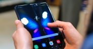 Mãos seguram um smartphone dobrável aberto, com a tela exibindo a imagem de uma borboleta.