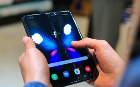 Mãos seguram um smartphone dobrável aberto, com a tela exibindo a imagem de uma borboleta.