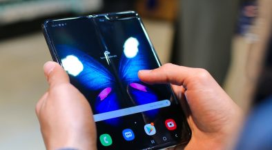 Mãos seguram um smartphone dobrável aberto, com a tela exibindo a imagem de uma borboleta.