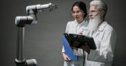 Pesquisadores examinam um braço robótico em um laboratório de tecnologia.