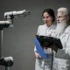 Pesquisadores examinam um braço robótico em um laboratório de tecnologia.