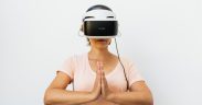 Mulher adulta medita usando um headset de realidade virtual diante de fundo branco.