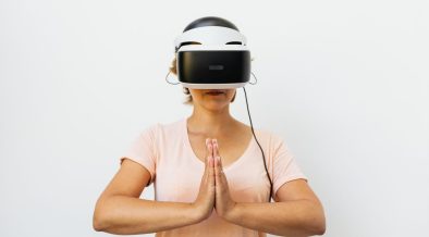 Mulher adulta medita usando um headset de realidade virtual diante de fundo branco.