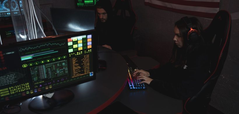 Profissionais de cibersegurança monitoram sistemas de computador em uma sala com iluminação baixa.