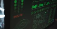 Tela de computador exibindo interfaces digitais de cibersegurança e proteção de dados em tons verdes.