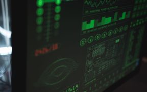 Tela de computador exibindo interfaces digitais de cibersegurança e proteção de dados em tons verdes.